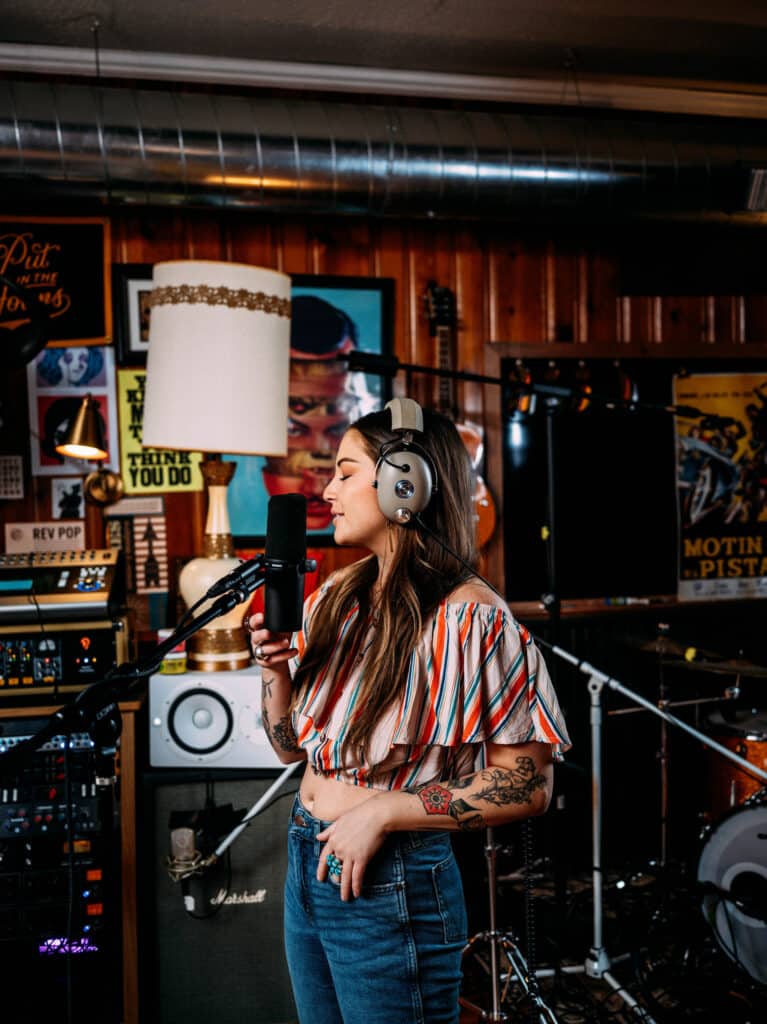 Woman at the studio expressing her creativity through music, singing into the mic. 