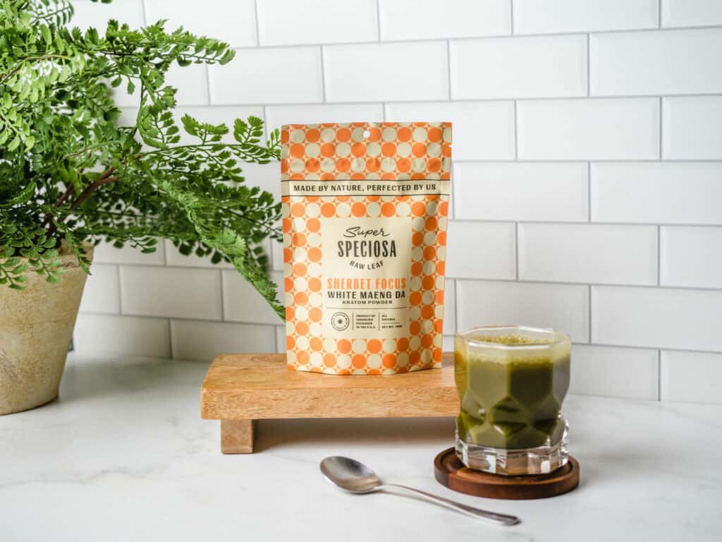 Super Speciosa Sherbert Focus Flavored Kratom Powder made from White Maeng Da Kratom, with cup of flavored kratom drink, a natural way to enhance your wellness with kratom supplements.
