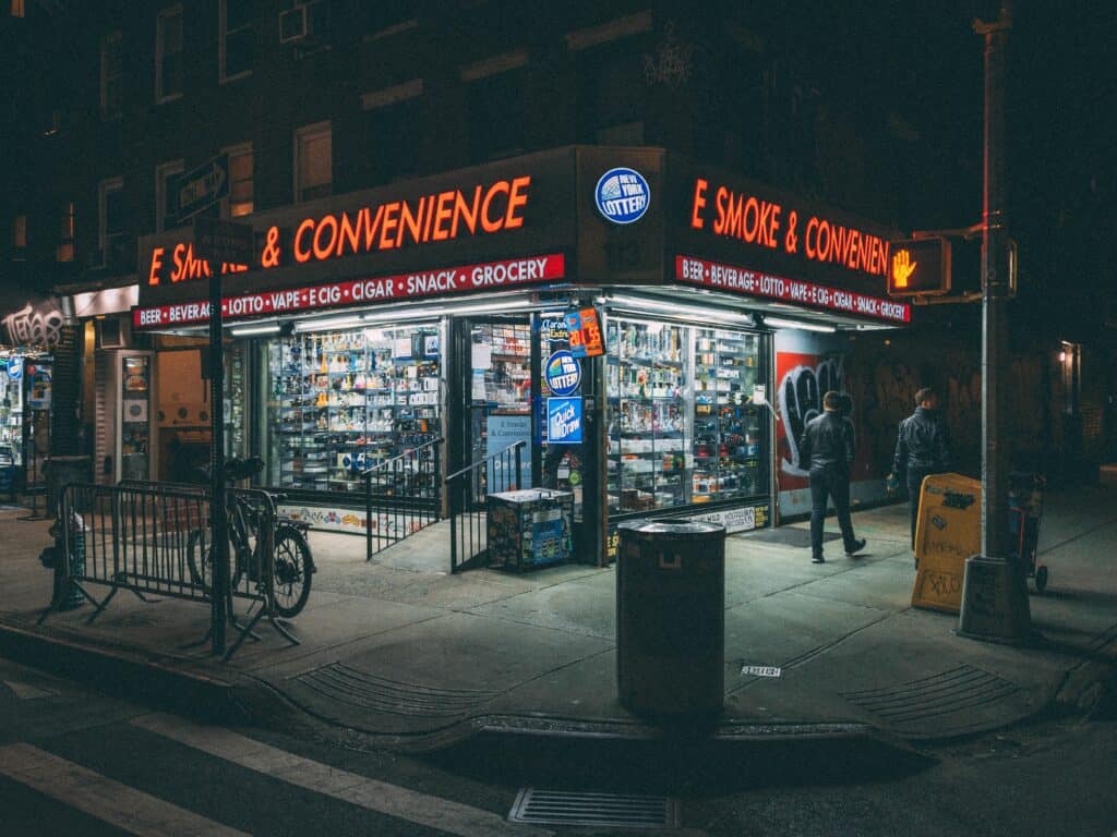 Corner smoke shop at night, in the East Village, Manhattan, New York City. Smoke shops sell kratom, vapes, cigars, and snacks.