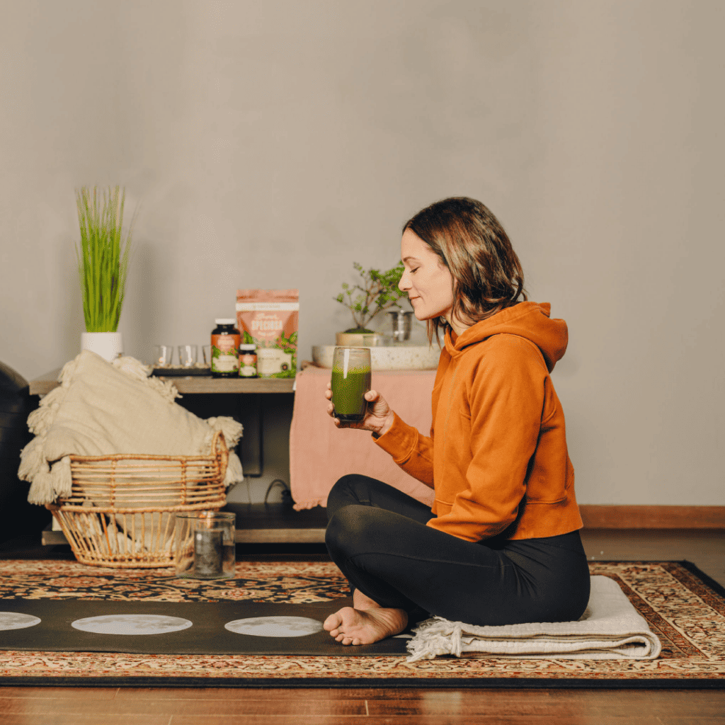 Woman is sitting with a cup of kratom drink, meditating. One of kratom's uses is for focus.