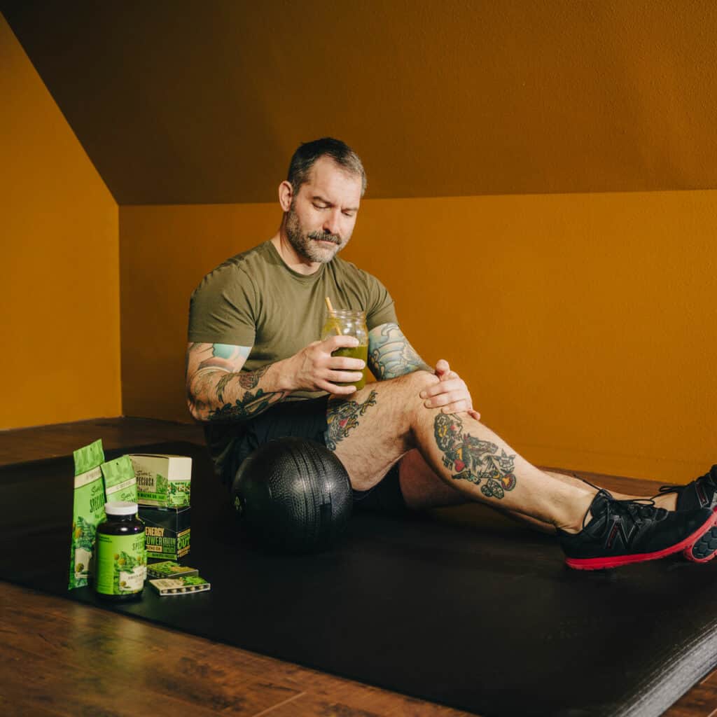 Man working out with kratom powder drink, preworkout supplement. Next to selection of Super Speciosa Green Maeng Da kratom products, kratom capsules, kratom tablets, kratom tea.