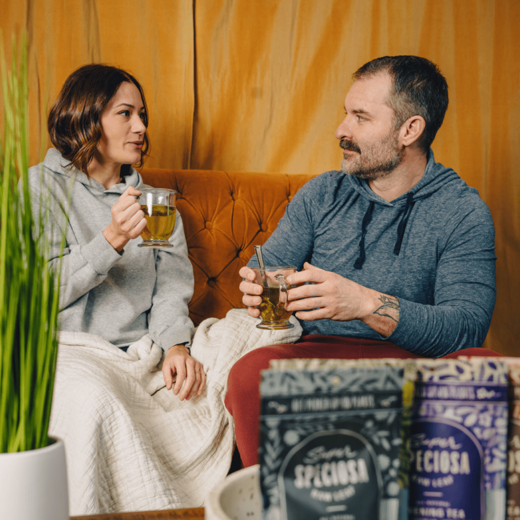 Couple sitting on couch relaxing with kratom tea. Relaxation is one reason why people use kratom.