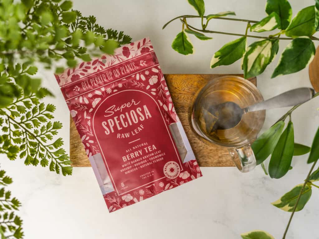 What is kratom tea? Super Speciosa's Berry herbal kratom tea blend with cup of kratom tea and greenery.