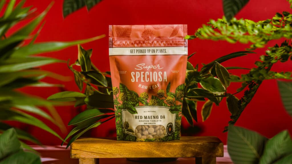 Super Speciosa's Red Maeng Da kratom tablets with red background and plants.