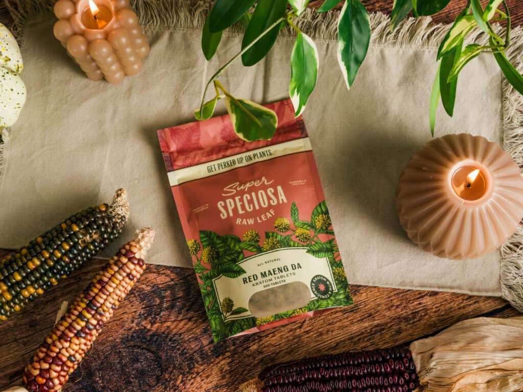 Super Speciosa's Red Maeng Da Kratom kratom tablets staged in an autumn setting. Red Maeng Da is one of the best kratom strains to buy in 2023.