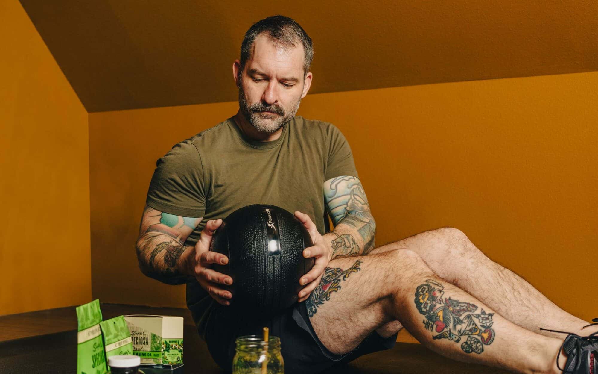 Man exercising while drinking green kratom drink and next to assortment of Green Maeng Da kratom products, like capsules, powder, and tablets. Green Kratom is used for energy.
