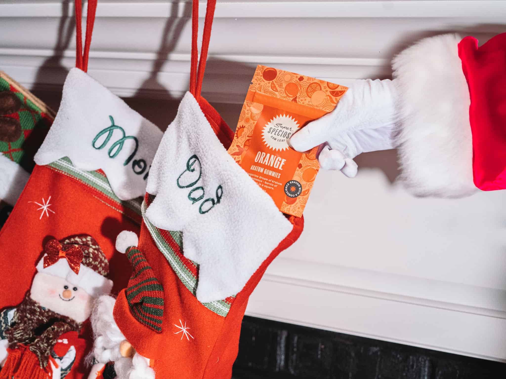 Santa adding orange kratom gummies to a stocking for a kratom stocking stuffer.