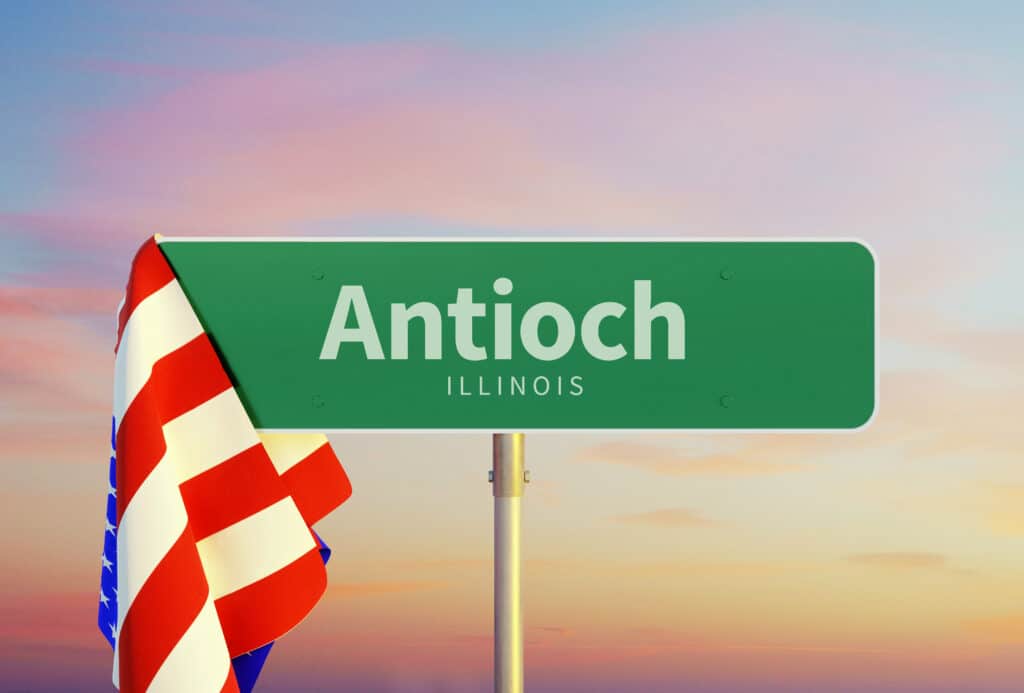 Antioch – Illinois. Road or Town Sign. Flag of the united states. Sunset oder Sunrise Sky. 3d rendering